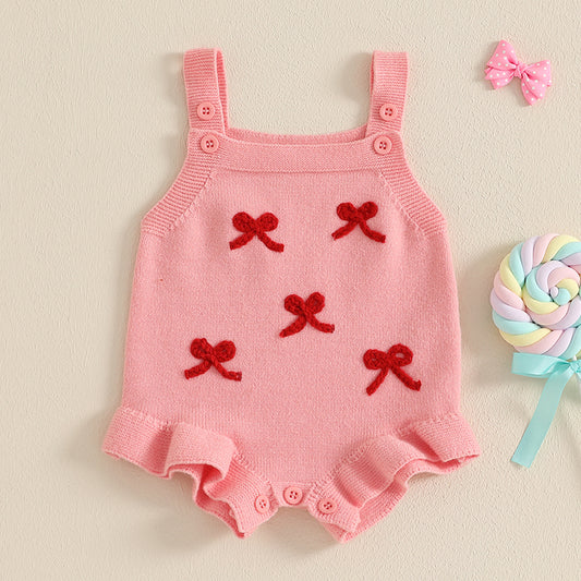 Pink baby romper with red bows on a beige background